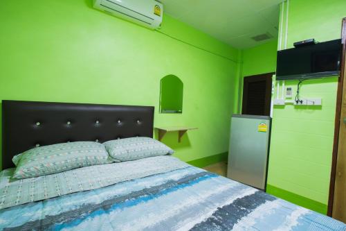 清莱您的家旅馆的一间卧室设有一张床和绿色的墙壁
