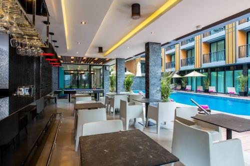 奥南海滩GLOW Ao Nang Krabi的一间带游泳池和桌椅的餐厅