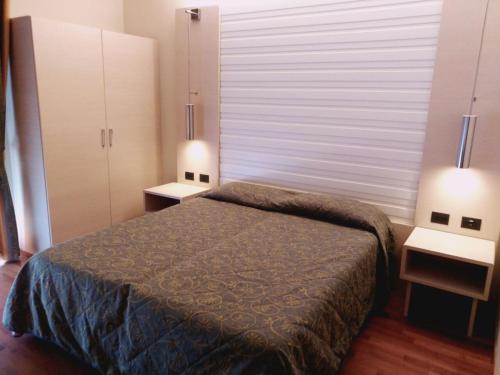 利尼亚诺萨比亚多罗哥伦布酒店的一间卧室配有一张床、两盏灯和一个窗户。