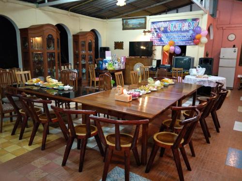 Phayayen巴耶延的言旅馆的用餐室配有大型木桌和椅子