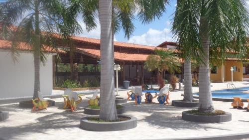 巴雷里尼亚斯Porto dos Lencóis - Chalé Tipo Apartamento的棕榈树和椅子以及游泳池的度假村