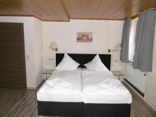 BühlertannGästepension zum Stern的一间卧室配有一张带白色床单的大床