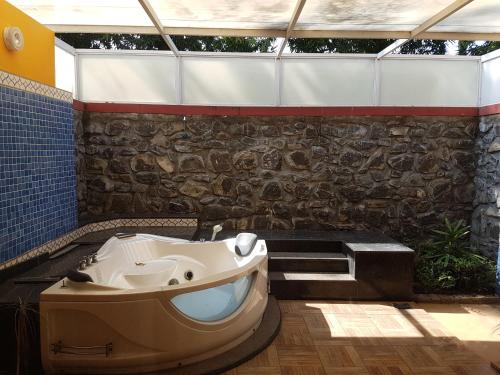 钦奈VGP黄金海岸度假酒店的带浴缸和石墙的浴室