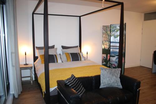 阿姆斯特丹The Water Studio的一间卧室配有一张大天蓬床和一张沙发