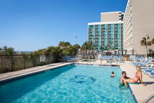 默特尔比奇蓝色酒店的坐在酒店游泳池里的家庭