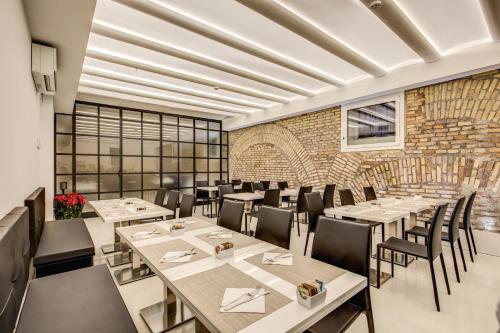 罗马自由精品酒店的一间带桌椅的餐厅以及砖墙