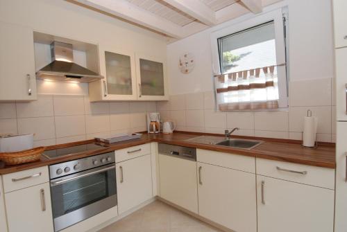 巴贝Strandpark Baabe Haus 224的厨房配有白色橱柜、水槽和窗户。