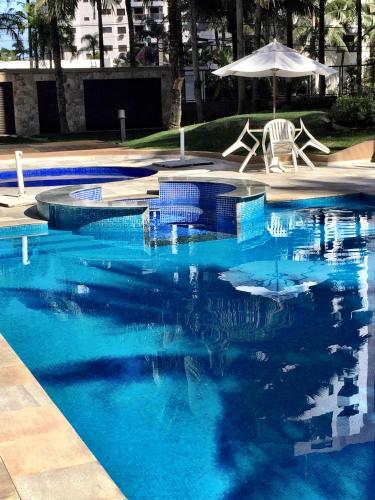 伯迪亚哥Riviera de São Lourenço的蓝色游泳池设有两把椅子和一把遮阳伞