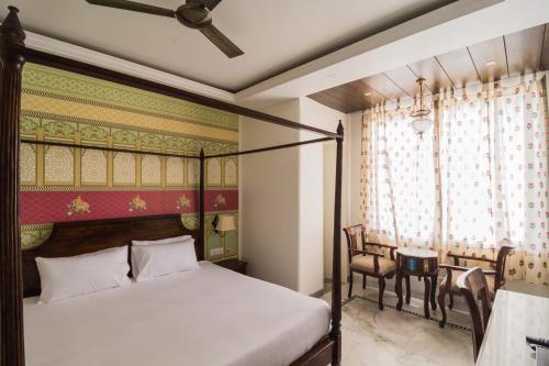 斋浦尔潘迪亚尼瓦酒店的一间卧室配有天蓬床和桌椅