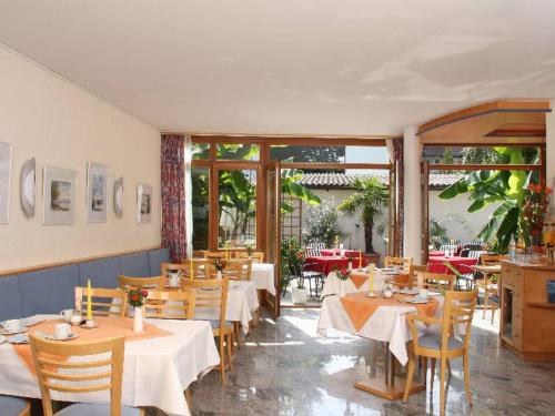 博登斯边的伊门施塔特溪柔思公寓式酒店的餐厅设有白色的桌椅和窗户。