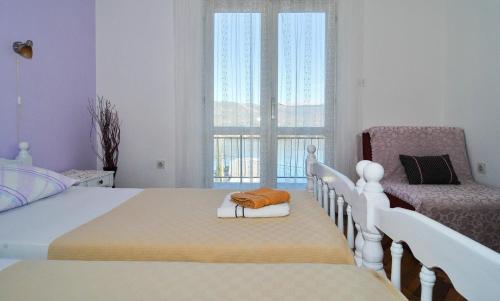 蒂瓦特Apartman Belami的一间卧室设有两张床、一把椅子和一个窗户。