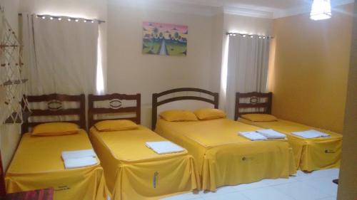 索布拉尔Pousada Aquino的一间设有三张黄色床单的房间