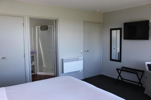 提马鲁逸景住宿加早餐酒店的卧室配有白色的床和平面电视。