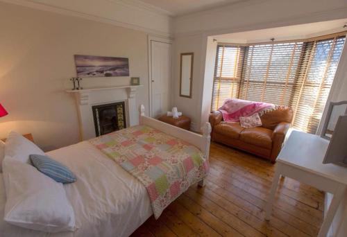 彭布罗克码头Holiday House Pembroke Dock的一间卧室配有一张床、一张沙发和一个壁炉