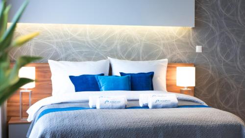 卡托维兹ActivPark Apartments的一间卧室配有一张带蓝色和白色枕头的床