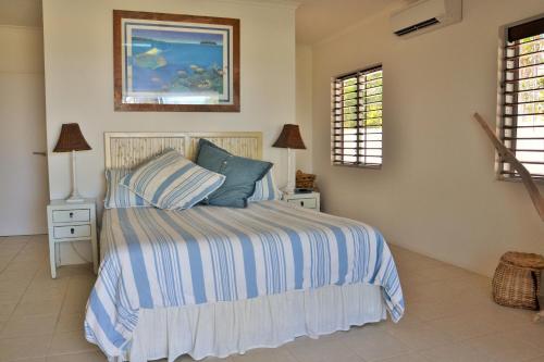 米申海滩Banfields Retreat的一间卧室配有带条纹被子的床和2扇窗户