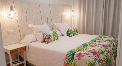 波多黎各格立玛公寓酒店的一间卧室配有带白色床单和热带枕头的床。
