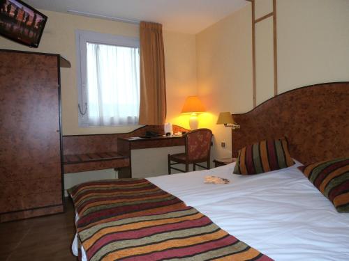 加来Logis Cottage Hôtel的配有一张床、一张书桌和一扇窗户的酒店客房