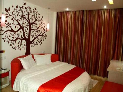 沧州尚客优连锁河北沧州解放西路店的卧室配有一张床铺,墙上挂着一棵树
