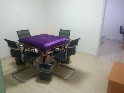 无锡尚客优连锁江苏无锡新区泰伯大道店的一张桌子,上面有椅子和紫色的桌布
