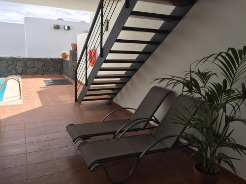 普拉亚布兰卡Villa Rubicon Playa的楼梯旁的天井配有两把椅子和植物