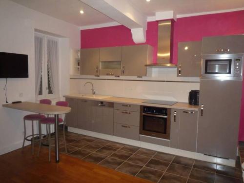 图尔尼TOURNUS Belle maison vue sur Saône的厨房设有粉红色的墙壁、桌子和冰箱