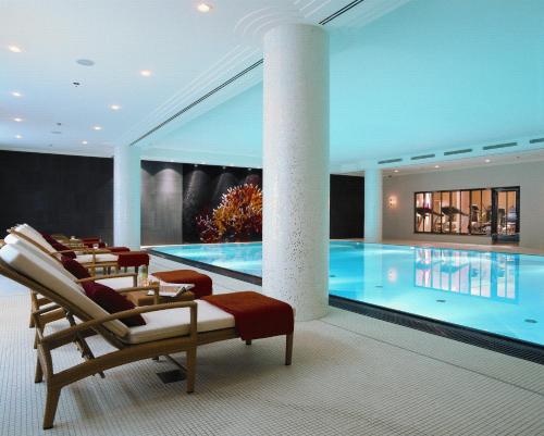 慕尼黑罗科洛克福特查尔斯酒店的一座带椅子和桌子的酒店游泳池