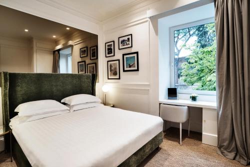 罗马希尔酒店的一间卧室配有一张床、一张书桌和一个窗户。