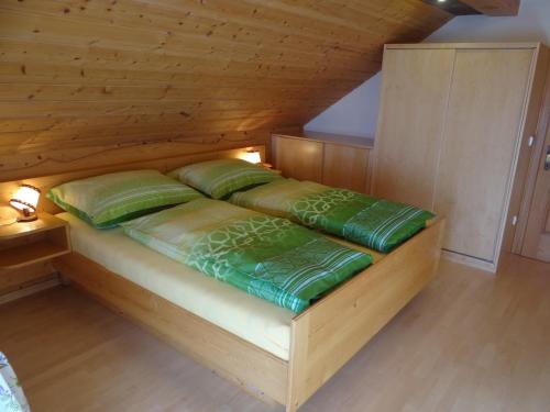隆高地区圣玛格丽滕雪绒花公寓的一张带绿色枕头的木床