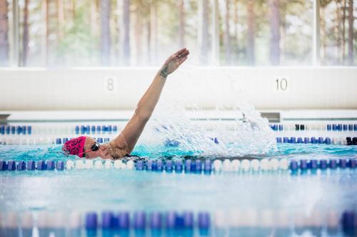 沃卡蒂Vuokatti Sport Chalets的女人在游泳池里,手臂在空气中