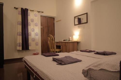 Kokkānisseri维雷特利特度假村的一间卧室设有两张床、一张桌子和一个窗口。