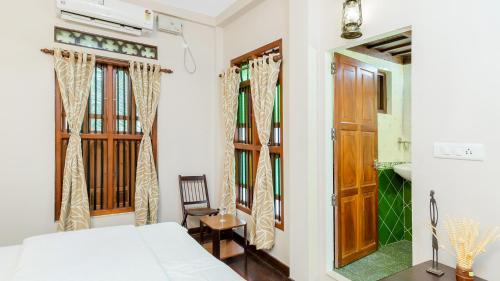 库玛拉孔Kumarakom Wood Castle Serviced Appartments的一间卧室配有一张床、一把椅子和镜子