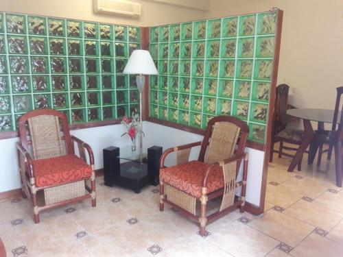 伊基托斯Amazon Green Hotel的一间设有两把椅子和一张桌子的房间,墙上设有玻璃墙