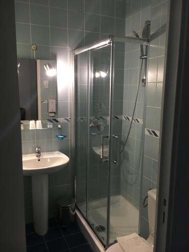 沙勒维尔-梅济耶尔塞萨尔酒店的一间带玻璃淋浴和水槽的浴室