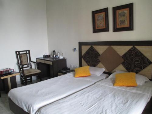 新德里东区度假酒店的一间卧室配有一张大床和两张黄色枕头