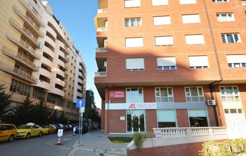 地拉那奥雷斯蒂中心酒店的一条城市街道上一座高大的砖砌建筑,有停放的汽车