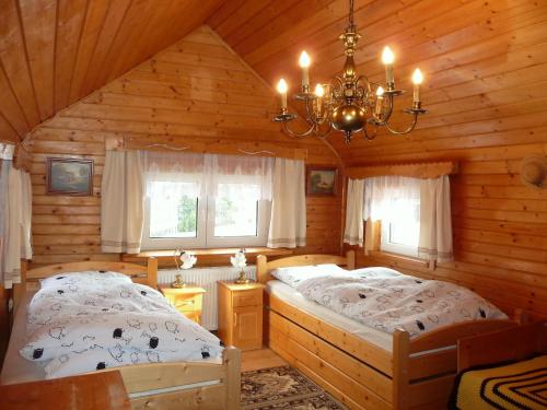 科尔别卢夫Apartamenty Widokowa的小木屋卧室内的两张床,配有吊灯