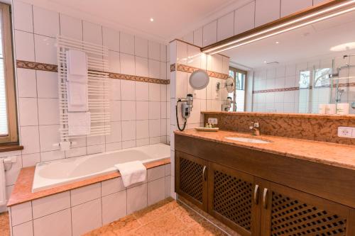 慕尼黑Hotel & Gaststätte zum Erdinger Weißbräu的带浴缸和盥洗盆的浴室