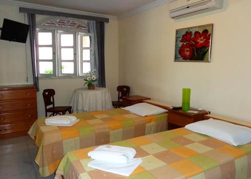 IgarassuPousada Monjope的酒店客房设有两张床和一张桌子。