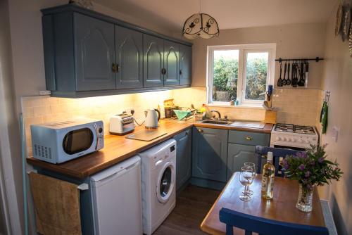 马林Barney's Lodge的厨房配有蓝色橱柜和带微波炉的桌子。