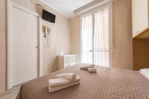 里米尼罗米纳酒店的卧室配有带2条毛巾的窗户,位于床上