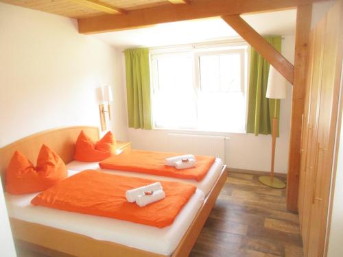 巴德米滕多夫埃米公寓的一间卧室设有两张带橙色床单的床和窗户。