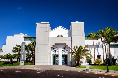 科斯塔特吉塞巴塞罗特吉塞海滩酒店 - 仅限成人的一座白色的建筑,前面有棕榈树