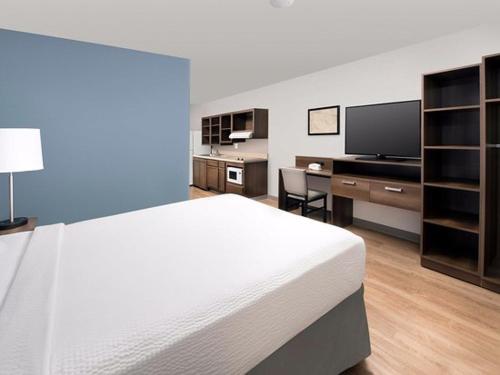 萨凡纳WoodSpring Suites Savannah Pooler的一间卧室配有一张床、一张书桌和一台电视。