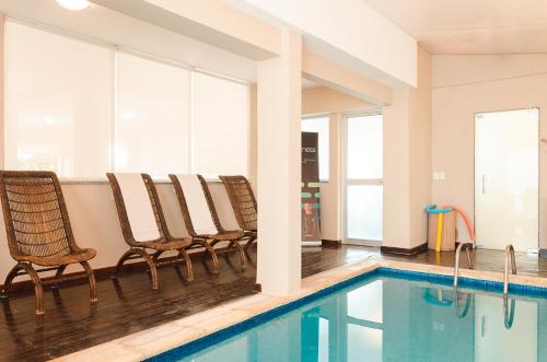 埃斯特角城日落海滩酒店 的游泳池旁带椅子的游泳池