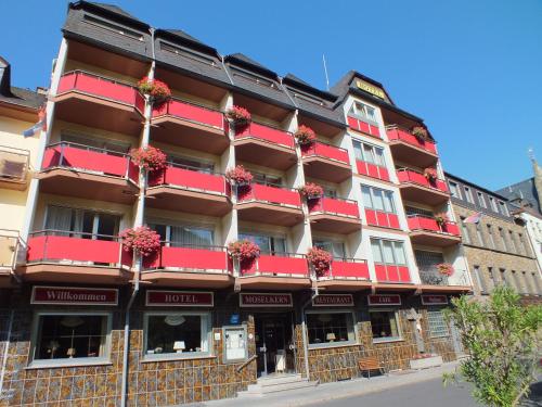 摩泽尔肯Hotel Moselkern的一座建筑,设有红色的阳台,并种植了鲜花
