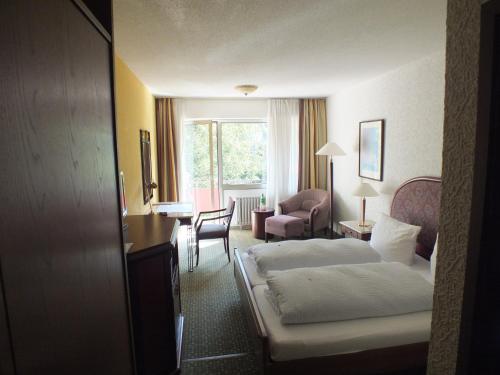 摩泽尔肯Hotel Moselkern的酒店客房,配有一张床、一张桌子和椅子