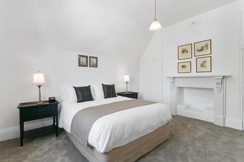 桑迪湾安伯利度假屋的白色卧室设有一张大床和一个壁炉