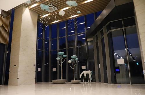 清州市J One Hotel Cheongju的大堂设有玻璃窗户和白色雕塑。