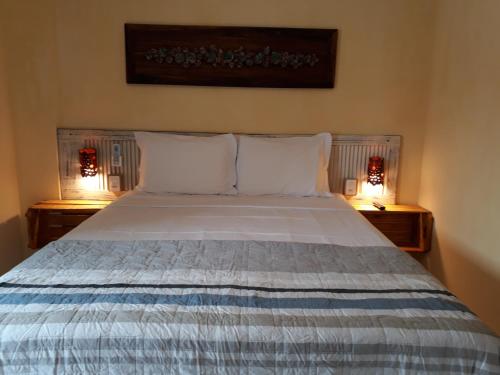 邦比尼亚斯Vila Artesania的卧室配有一张床,两边都配有两盏灯